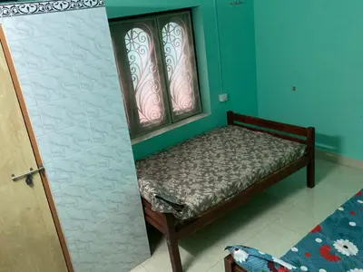 a small bed in a room with two windows at nandanam villlas in Guruvāyūr
