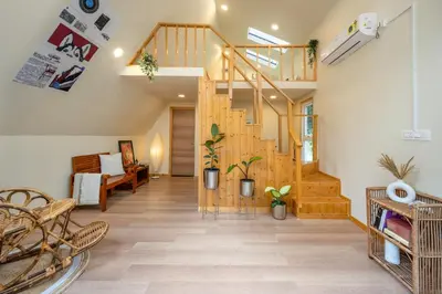 a living room with a wooden staircase in a house at Lolo's by Raho - Loft Stay in Coorg in Ammatti