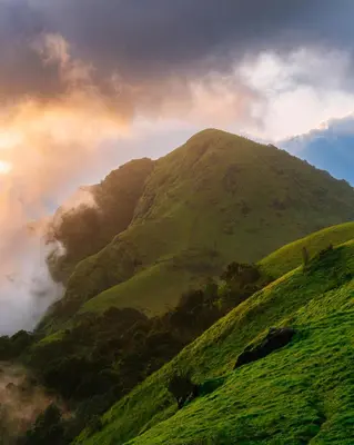 a green mountain with a rainbow in the sky at Lolo's by Raho - Loft Stay in Coorg in Ammatti