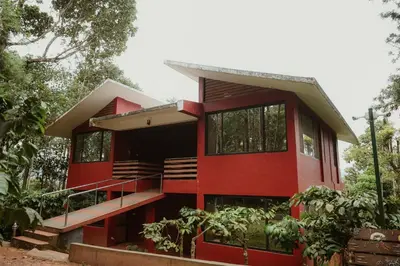 a red house in the middle of a forest at Greenex farm Resort in Vythiri