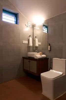 a bathroom with a toilet and a sink and a mirror at Nila by Raho - Secluded Villa with Estate View in Siddapur