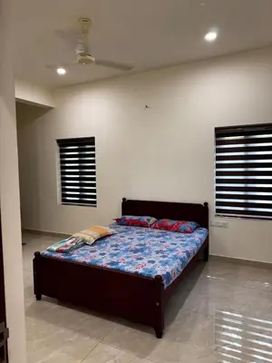 a bedroom with a bed in a room with windows at Calm Serenity Homestay in Kozhikode