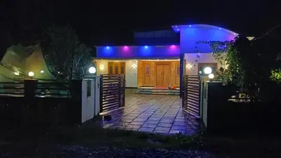a house lit up at night with blue lights at Sai home stay & service villa in Koroth