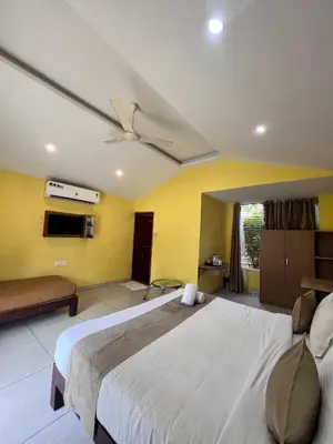 a bedroom with a large bed and a ceiling fan at Plumeria Resort Coorg in Kushālnagar