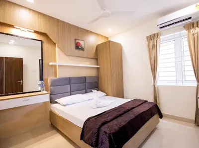 a bedroom with a bed with a mirror and a window at Sree Home Stay and Service Apartment in Coimbatore