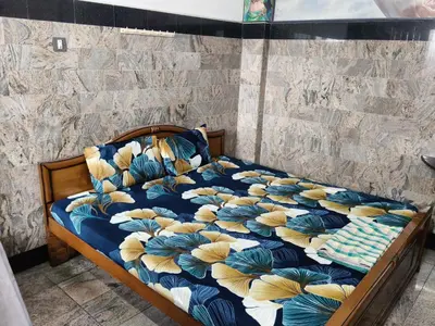 a bed with a blue and yellow comforter at Hotel Nirmal Cottage Gobichettipalayam in Siruvalūr