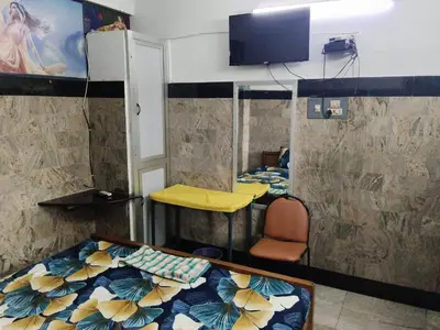a room with a bed and a chair and a tv at Hotel Nirmal Cottage Gobichettipalayam in Siruvalūr