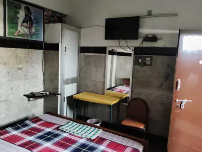 a room with a bed and a table and a mirror at Hotel Nirmal Cottage Gobichettipalayam in Siruvalūr