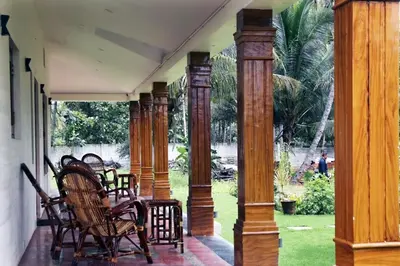 a porch with wooden columns and chairs on it at Nirmala Dhama Farmstay - Serene Family Retreat