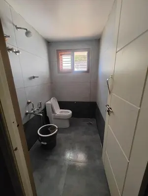 a small bathroom with a toilet and a window at Nirmala Dhama Farmstay - Serene Family Retreat