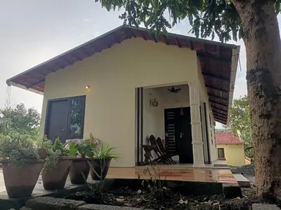 a small white house with plants in front of it at Nihave in Attappādi