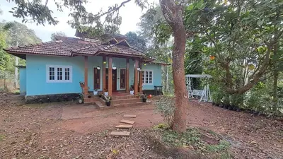 a small blue house with a tree in front of it at Aura Eco Friendly Resort in Sultan Bathery