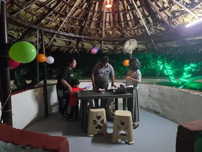 a group of people standing around a table with balloons at Mango Bite Farmstay in Pollāchi