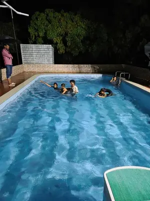 a group of people swimming in a swimming pool at Mango Bite Farmstay in Pollāchi