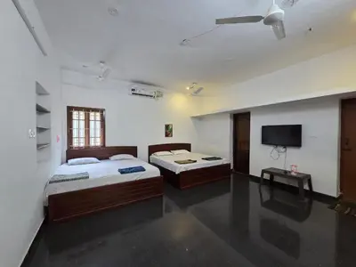 a bedroom with two beds and a flat screen tv at Mango Bite Farmstay in Pollāchi