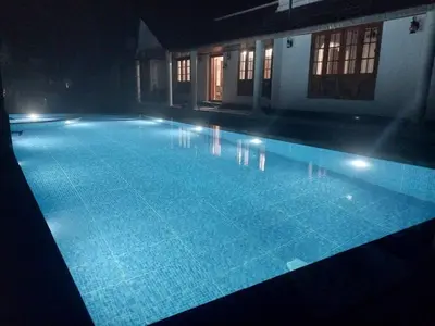 a large swimming pool at night with lights on it at Salisbury Manor Heritage Inn in Marayoor