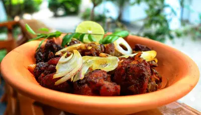 an orange bowl of food with meat and vegetables at Salisbury Manor Heritage Inn in Marayoor