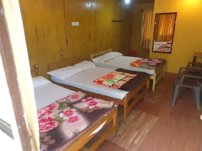 a room with three beds and a chair at Jungle Mist Cottages in Masinagudi