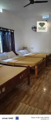 two twin beds in a room with avertisement at Jungle Mist Cottages in Masinagudi
