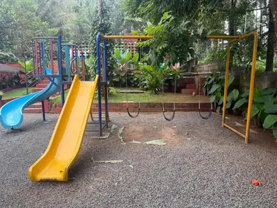 a playground with a yellow slide in a park at Wayanad Shas Villa in Padinjarathara