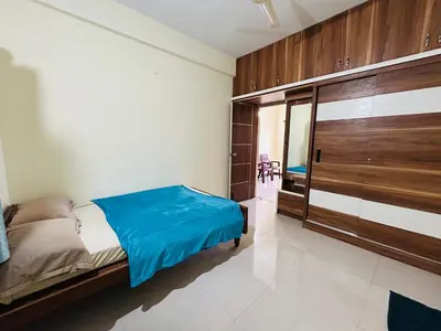 a bedroom with a bed and a large wooden closet at Raya 2 bhk flats in Mysore