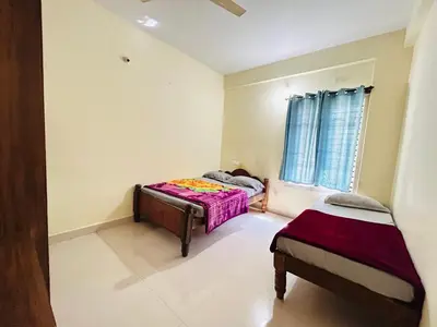 a bedroom with two beds and a window at Raya 2 bhk flats in Mysore