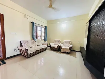 a living room with two chairs and a flat screen tv at Raya 2 bhk flats in Mysore
