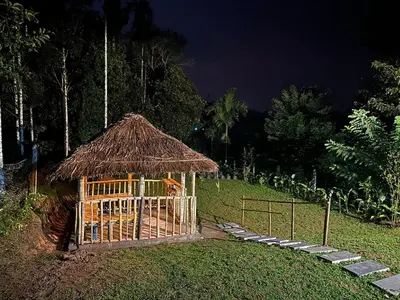 a gazebo with a straw roof in the grass at Vathika Villa in Sultan Bathery