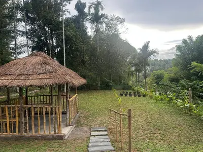 a hut with a grass roof in a field at Vathika Villa in Sultan Bathery
