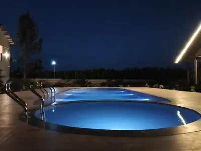 a large blue swimming pool at night at The fox resort in Bandipūr