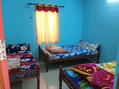 a room with two beds and a blue wall at Shobha home stay in Vattavada