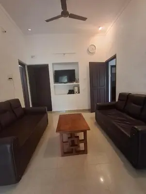 a living room with two black couches and a coffee table at Winter Valley Home Stay in Vythiri