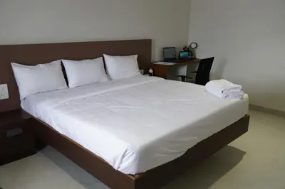 a bedroom with a large bed with white sheets and pillows at KK Service Suites in Coimbatore
