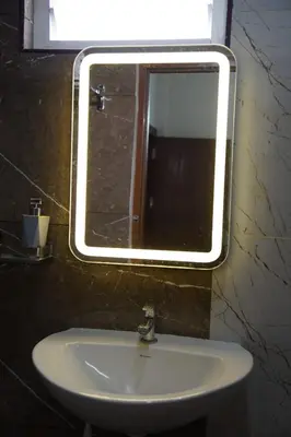 a mirror above a white sink in a bathroom at KK Service Suites in Coimbatore