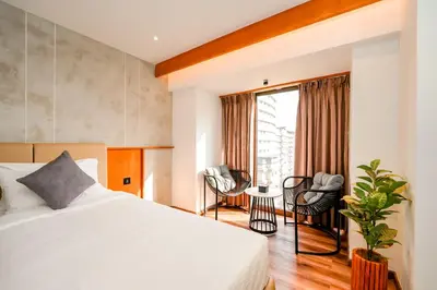 a bedroom with a bed and two chairs and a window at Nestlay Suites by TC One in Kozhikode
