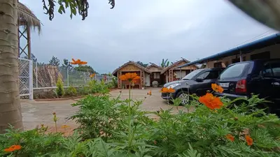 a parking lot with cars parked in front of a building at Magizh Kudil The Mud House in Marayoor