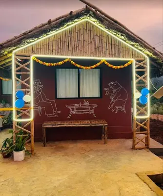 a shed with a bench in front of it with lights at Magizh Kudil The Mud House in Marayoor