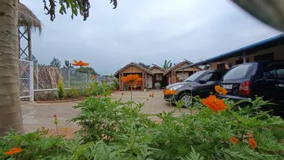 a parking lot with cars parked in front of a building at Magizh Kudil The Mud House in Marayoor