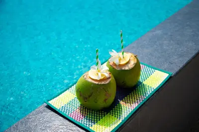 two green apples sitting on a table next to a pool at Pollachi Riverhouse, A CGH Earth Saha experience in Pollāchi