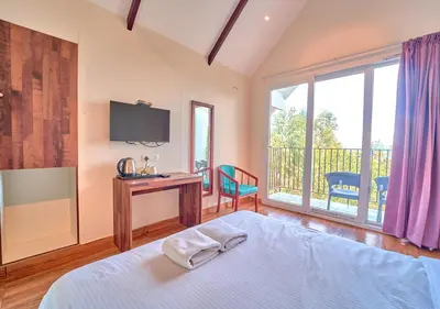 a bedroom with a bed and a desk and a television at Gardenia Pool Resort Kanthalloor by VOYE HOMES Mountain View Stay Near Bhramaram view Point in Kanthalloor