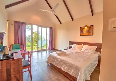 a bedroom with a large bed and a desk and a window at Gardenia Pool Resort Kanthalloor by VOYE HOMES Mountain View Stay Near Bhramaram view Point in Kanthalloor