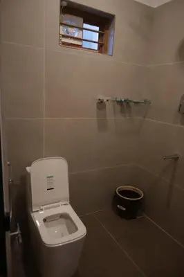 a bathroom with a white toilet and a window at Castle DAK in Trichūr