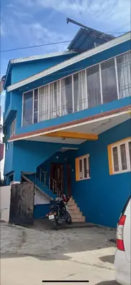 a blue house with a motorcycle parked in front of it at DADIL HOME STAY ooty in Ooty