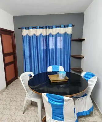 a dining room table with chairs and a blue curtain at DADIL HOME STAY ooty in Ooty