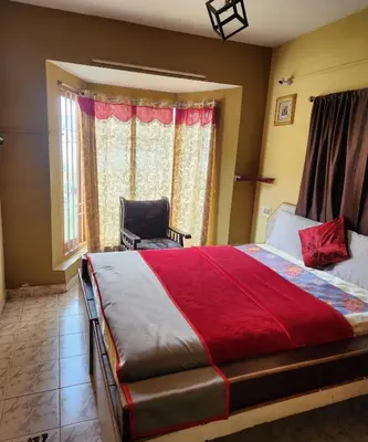 a bedroom with a large bed and a chair at DADIL HOME STAY ooty in Ooty