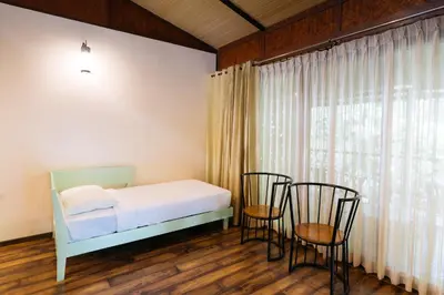 a bedroom with a bed and two chairs and a window at Discovery Village Kabini in Antarasante