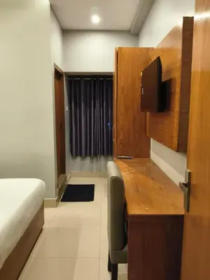 a room with a desk and a bed and a desk and a chair at Hotel Riviera in Mananthavady