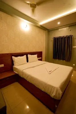 a bedroom with a large bed with white sheets at Hotel Riviera in Mananthavady