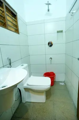 a bathroom with a white toilet and a sink at Hotel Riviera in Mananthavady