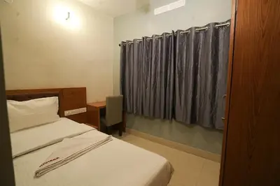 a bedroom with a bed and a window with curtains at Hotel Riviera in Mananthavady